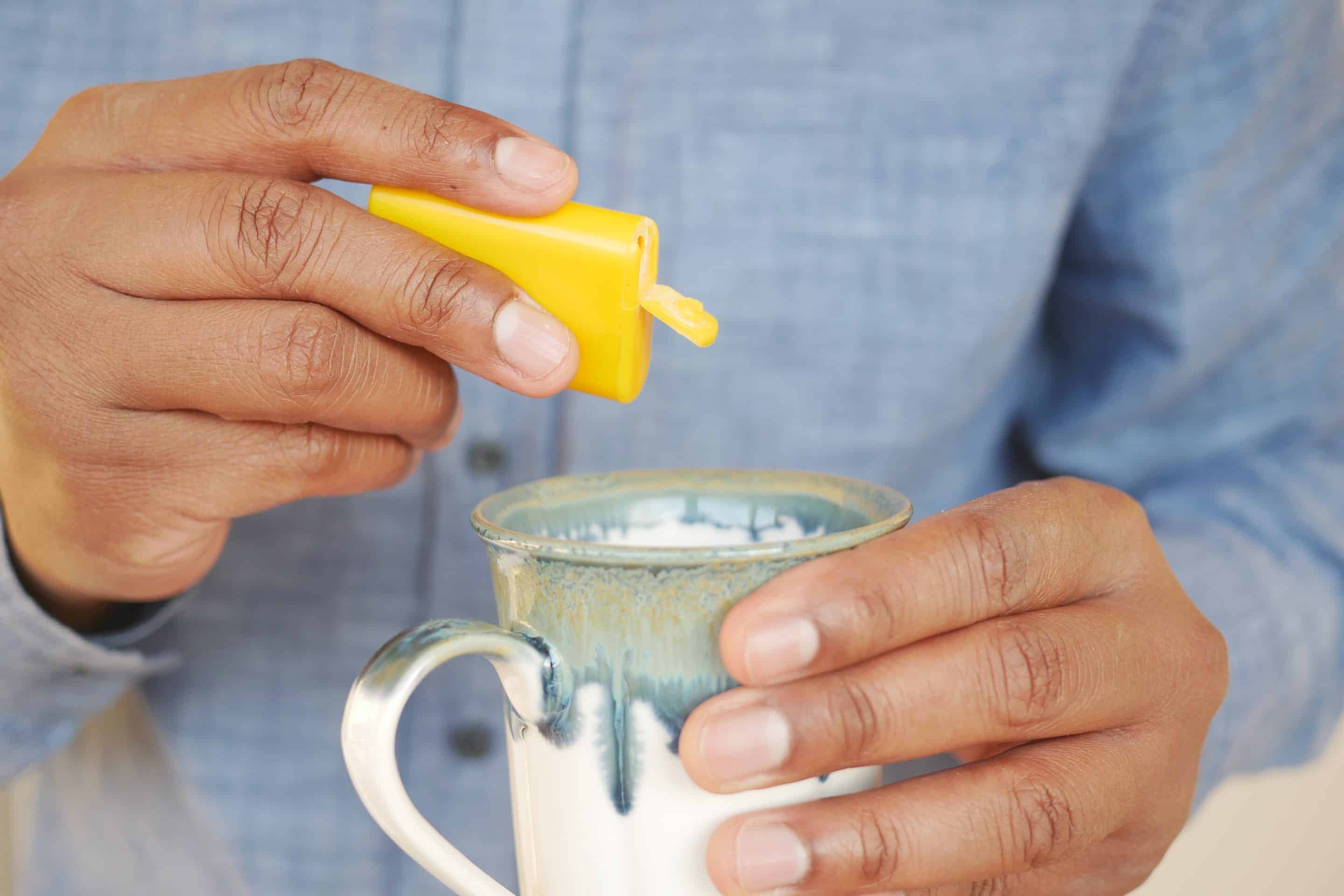 man putting artificial sweetener in tea